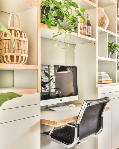 Ein kleiner Schreibtisch aufgebaut in einem Regal mit vielen Pflanzen