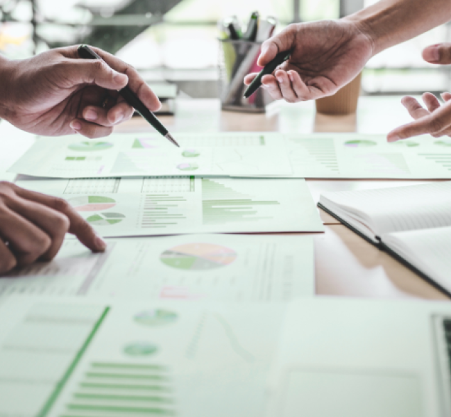 Personen die über einem Tisch mit vielen Zetteln diskutieren.