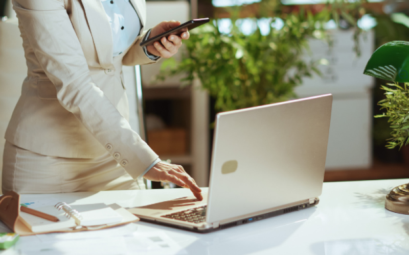 Eine Person sitzt an einem Tisch mit einem Taschenrechner, Notizbuch und Zetteln. Ein Stapel Geld liegt im Vordergrund