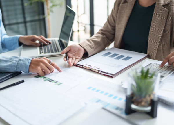 Zwei Personen in Business-Kleidung an einem Schreibtisch, offensichtlich am Arbeiten.